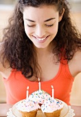 Woman holding plate of cupcakes with candles