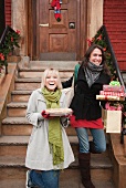 Zwei Frauen verlassen das Haus mit Weihnachtsgeschenken und Kuchen