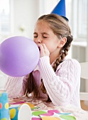 Young girl blowing up balloon