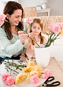 Mutter und Tochter arrangieren Blumen in einer Vase