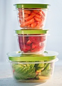 Carrots, strawberries and salad in plastic containers, studio shot