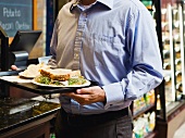 Mann trägt ein Tablett mit Sandwiches