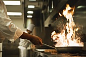 Chef holding flaming pan