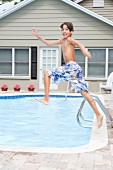 Voller Energie ins Wasser springender Junge