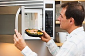 Man inserting meal in microwave oven