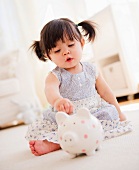 Baby spielt mit Sparschwein