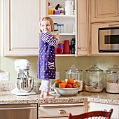 USA, Utah, Girl (2-3) climbing on cupboard in kitchen