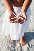 Girl on beach holding delicate starfish