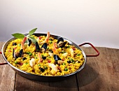 Paella in a pan on a wooden table