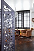 View into office with grey, metal screen; dark, exotic wood parquet floor and brown leather armchairs