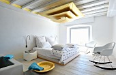 Pendant lamp made from three suspended gold sails in Mediterranean bedroom with Bauhaus rocking chair in front of double bed