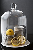 Lemons studded with cloves and muffin tins under a domed glass cover