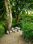 Gravel path & stone mushroom ornaments in garden