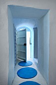 Blue, circular rugs in narrow corridor with open batten door at one end
