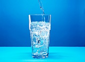 Mineralwasser ins Glas eingießen