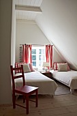 Kleines Gästeschlafzimmer unterm Dach in schlichtem Weiß mit roten Farbakzenten