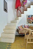 Frauenbeine auf betonierter Treppe im Wohnraum mit Holzstuhl und Sitzbank