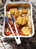 Barbecued potatoes and peppers in an aluminium tray on the barbecue