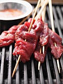 Raw satay skewers on the barbecue