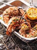 Barbecued king prawns in an aluminium tray on the barbecue