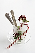 Holly berries, cutlery and candy cane in ice goblet