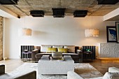 Loftartiger Wohnraum mit kubischem Couchtisch vor eleganter Sofagarnitur zwischen Designer Leuchten