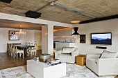 Loft-style interior with cubic coffee table and elegant armchairs in lounge area; dining area with Neo-Rococo chairs in background