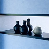 Harmonious composition of light and dark contrasts; ceramic vases on wooden coping of wall