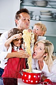 Familie spielt mit Spaghetti auf Arbeitsplatte in der Küche