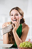 Germany, Young woman grating cheese, smiling