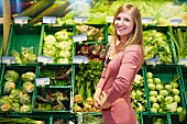 Germany, Cologne, Young woman in supermarket, smiling, portrait