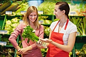 Germany, Cologne, Young womens with celery in supermarket
