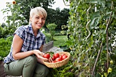 Germany, Bavaria, Nuremberg, Mature woman with vegetables in garden
