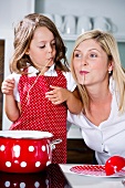 Germany, Mother and daughter eating noodles in kitchen