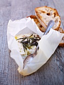 Goat cheese with rosemary and olive oil in parchment paper
