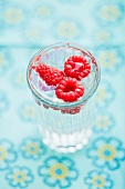 A glass of water with raspberries