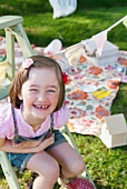 Smiling girl sitting on ladder in garden