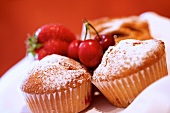 Muffins dusted with icing sugar, with cherries and a strawberry