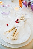 A Christmas place setting with cutlery, a napkin and a ribbon