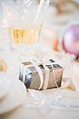 Weihnachtsgeschenk, Weinglas und Christbaumkugeln auf Tisch