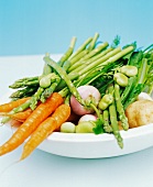 Close up of a bowl filled with spring vegetables including carrots, beans, asparagus, turnip and potatoes