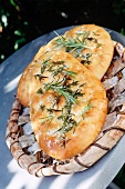 two Italian foccacia breads outside on a wooden tray