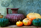 old terracotta jug with orange and green pumpkins