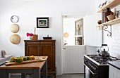 Helle Küche im Vintagelook mit Retro Gasherd und einfachem Holzregal an weiss gekachelter Wand