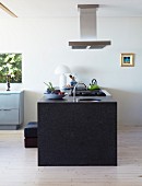 Freistehender Küchenblock aus Granit unter Dunstabzug in minimalistischem Wohnraum