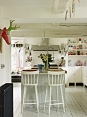 Spacious kitchen with central island, white walls and white-painted furniture