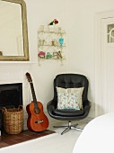 Swivel chair, guitar, wall-mounted shelves and open fireplace in corner of room