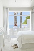Turnschuhe auf Flokatiteppich in weißem Designer Schlafzimmer mit Glasfront und Blick auf das Meer