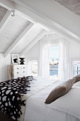 Relaxing holiday atmosphere in white bedroom with view of sea and rocks