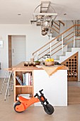 Open-plan interior with staircase and kitchen island below stainless steel pots and pans hanging from rack